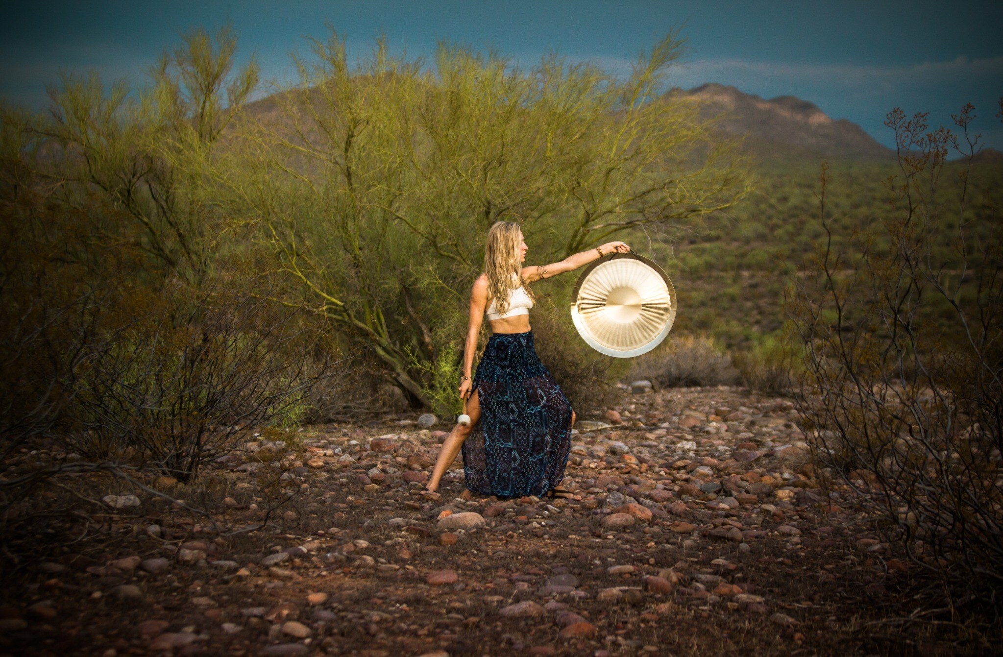 Lauren holding a gong in the desert landscape